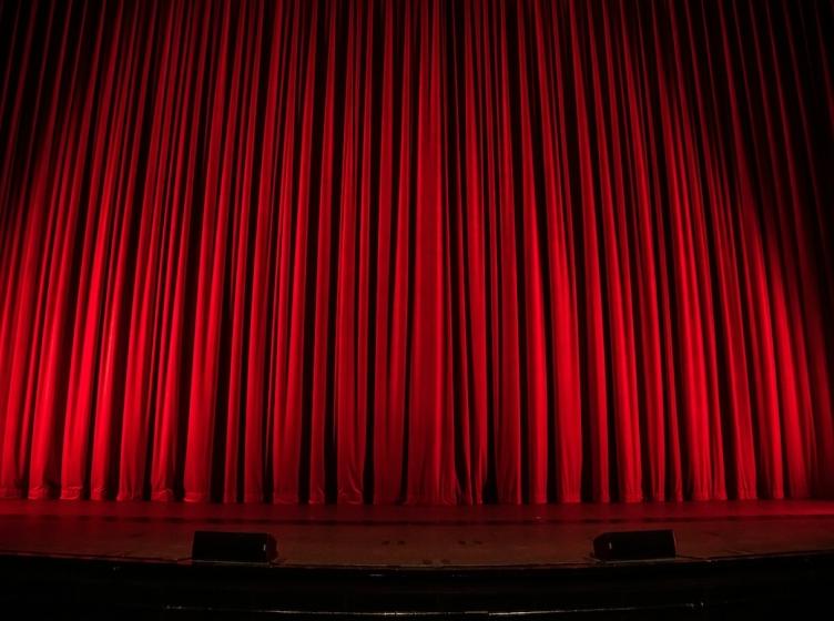 A theater stage with a closed red curtain