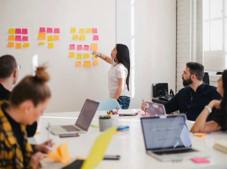 Woman leading meeting in conference room with post-it notes on a whiteboard